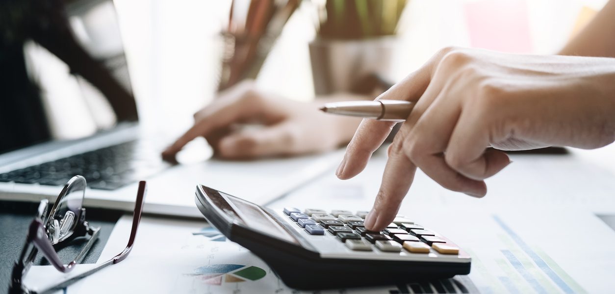 Close up Business woman using calculator and laptop for do math finance on wooden desk in office and business working background, tax, accounting, statistics and analytic research concept